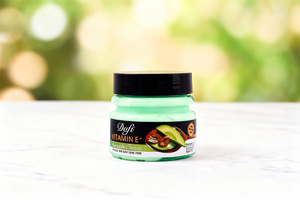 تصویر کرم ویتامین ای و آووکادو دافی کاسه ای روی سطح مرمر سفید