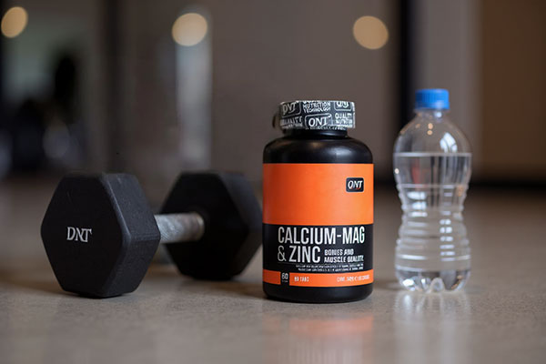 قرص کلسیم منیزیم و زینک کیو ان تی کنار تجهیزات ورزشی