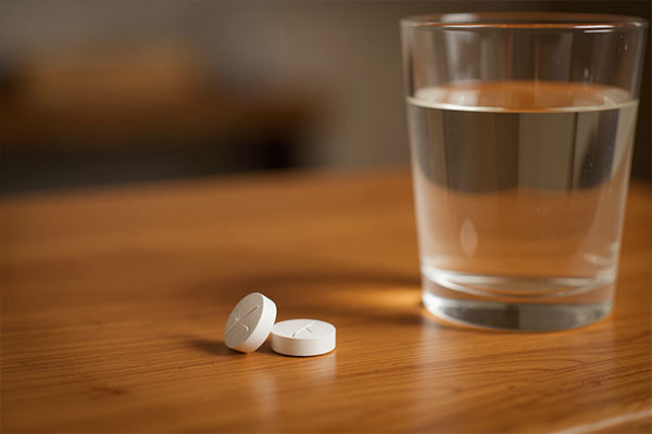 قرص فولیک اسید های هلث کنار لیوان آب