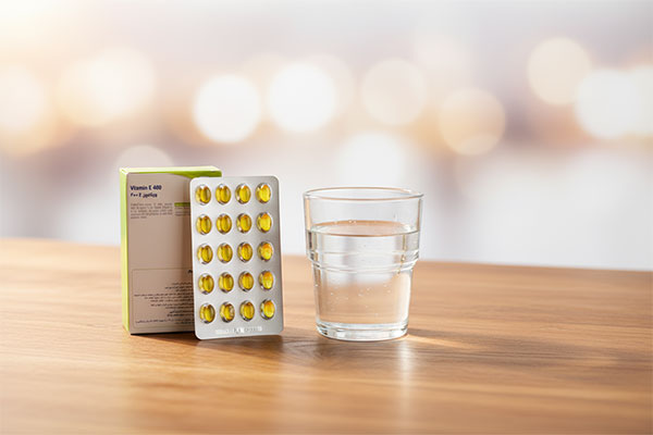 کپسول ویتامین ای یوروویتال کنار لیوان آب