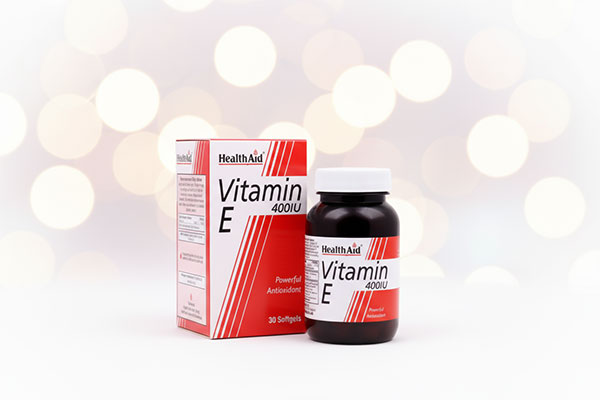 کپسول ویتامین E 400 هلث اید روی سطح سفید