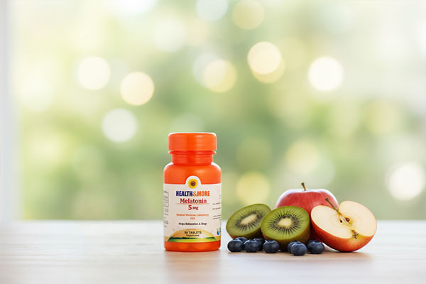 قرص مولتی ویتامین هلث اند مور در کنار مواد غذایی سالم