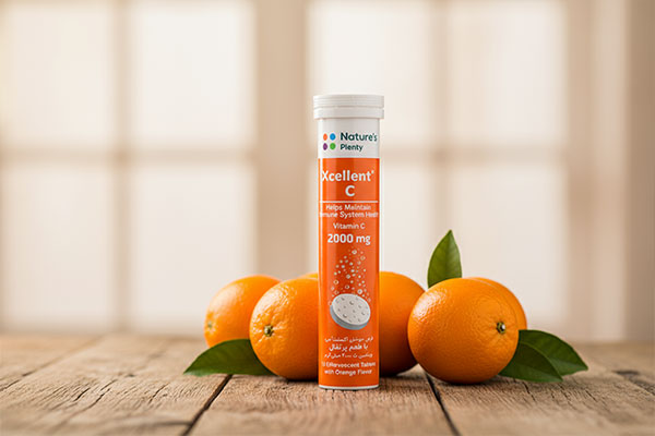بسته‌بندی قرص جوشان اکسلنت ویتامین سی با پرتقال در پس‌زمینه