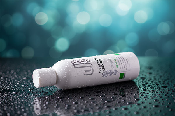 نمای نزدیک شامپو ضد ریزش کافئین دلانو با قطرات آب