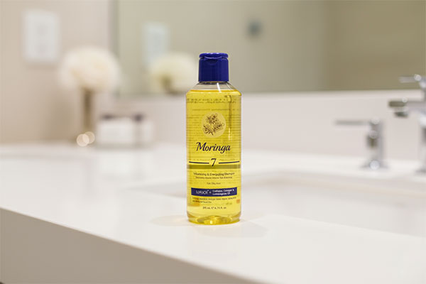 شامپو حجم دهنده موهای چرب شماره ۷ مورینگا روی پیشخوان حمام
