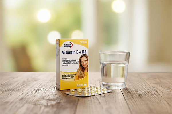 کپسول ویتامین ای و د3 یوروویتال کنار لیوان آب