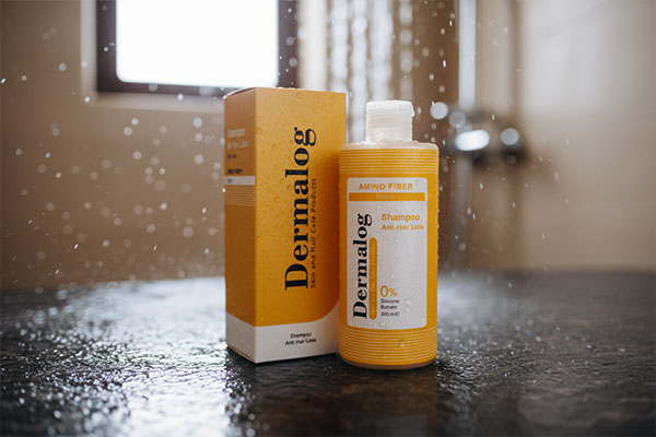 نمای نزدیک شامپو ضد ریزش درمالوگ با قطرات آب