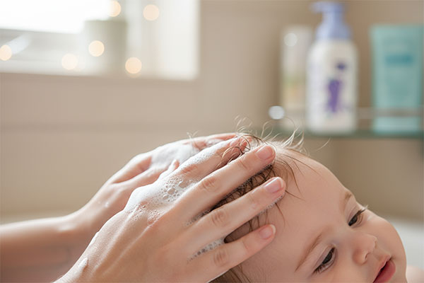 شامپو فوم نوزاد بیبی فرست در حال ماساژ روی پوست سر نوزاد