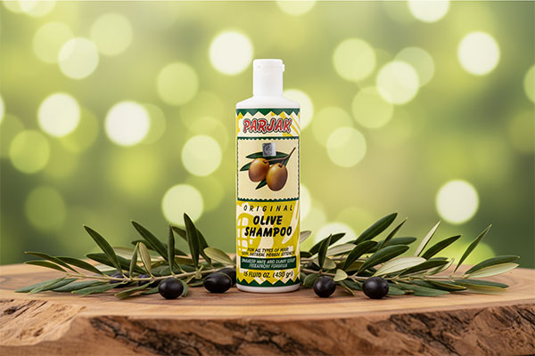 شامپو زیتون پرژک روی سطح چوبی با شاخه&zwnj;های زیتون
