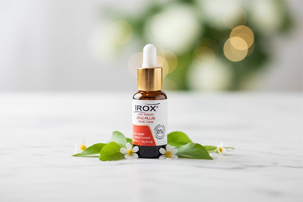 بطری سرم موی زینک پلاس ایروکس با قطرهچکان روی سطح مرمر سفید