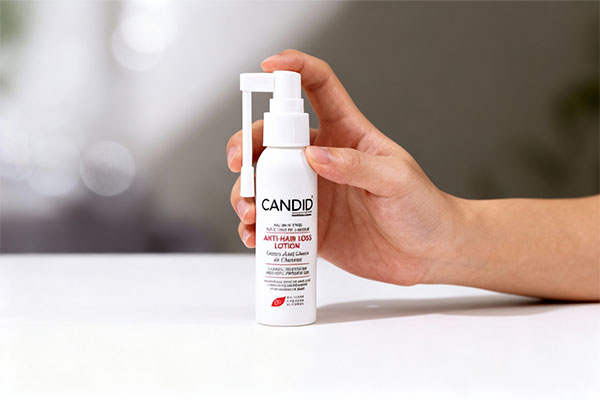 دست نگه داشتن بطری لوسیون تقویت کننده مو کاندید