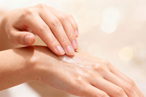 دست در حال استفاده از لوسیون بدن آکوا تاچ ویکتوریا رز برای آبرسانی پوست