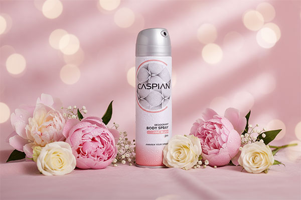 اسپری بدن زنانه با رایحه دل‌انگیز روی سطح صورتی