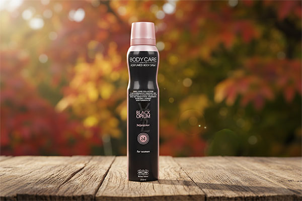 اسپری بدن زنانه بلک اپیوم بادی کر روی میز چوبی با پس‌زمینه پاییزی