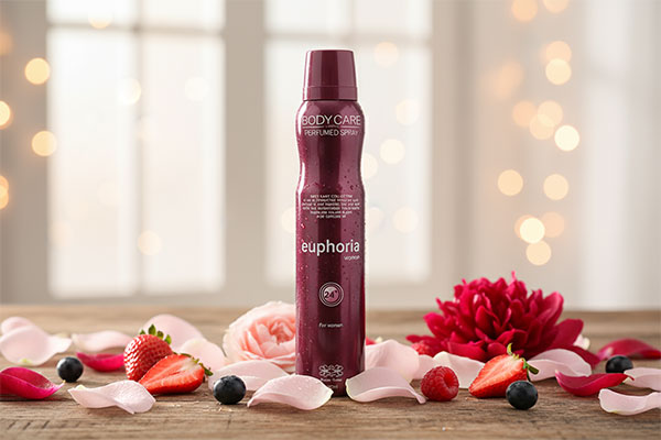 اسپری بدن زنانه ایفوریا بادی کر کلوین کلین روی میز چوبی با گل و میوه