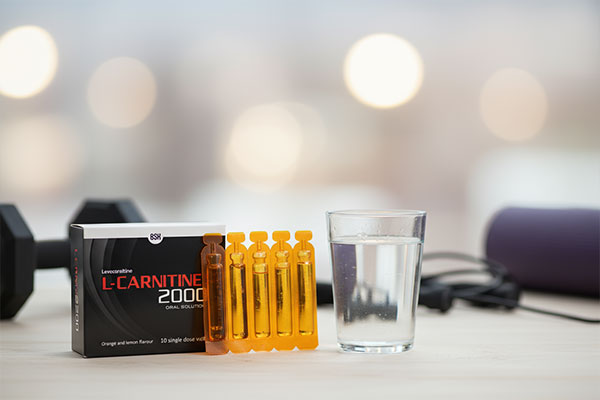 ویال ال‌ کارنیتین 2000 بی اس کی کنار لیوان آب و تجهیزات ورزشی