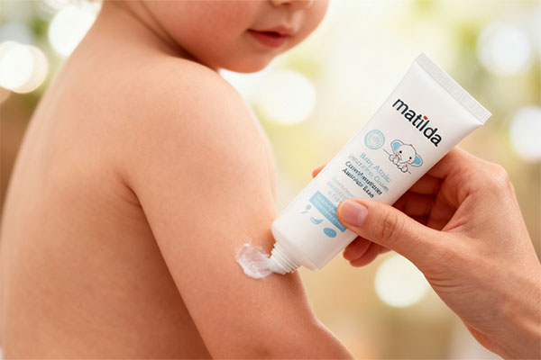 دست والدین در حال استفاده از کرم مرطوب کننده آتوپیک ماتیلدا روی پوست کودک