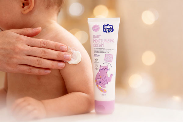 دست مادر در حال استفاده از کرم مرطوب کننده کودک بیبی فرست روی پوست نوزاد