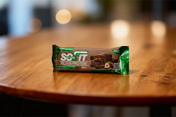 پروتئین بار با روکش کاکائویی تلخ سوفیت پلاس روی میز چوبی