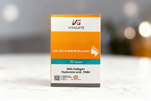 تصویر قرص مولتی ویتامین پوست و مو و ناخن ویتاگیت روی سطح مرمر سفید