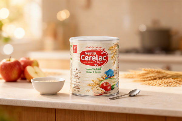 سرلاک گندم و سیب نستله کنار ظرف و قاشق کودک