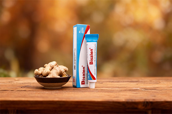 پماد بیزالن نوتک فار کنار ریشه زنجبیل روی میز چوبی