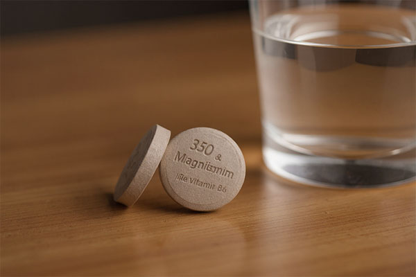 تصویر قرص منیزیم 350 و ویتامین ب6 کنار لیوان آب