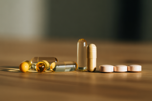 انواع مکملهای ویتامین B1 شامل قرص و کپسول روی میز چوبی